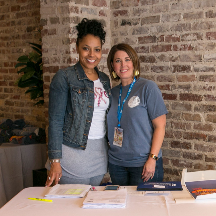 Two ladies standing at a table at the Tamale Festival